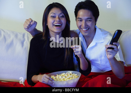 Couple watching TV, making fists, smiling Stock Photo
