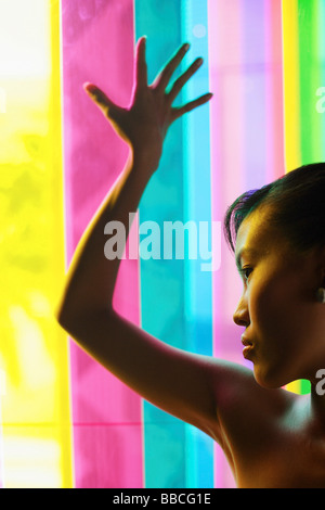 Woman leaning hand against coloured glass Stock Photo