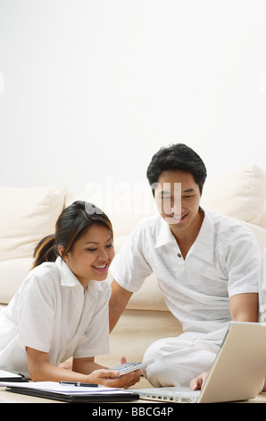 Couple at home in living room, looking at laptop Stock Photo