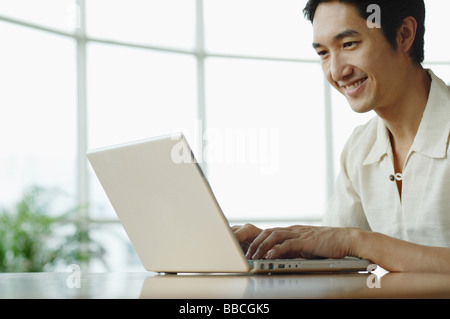 Man sitting, using laptop, smiling Stock Photo
