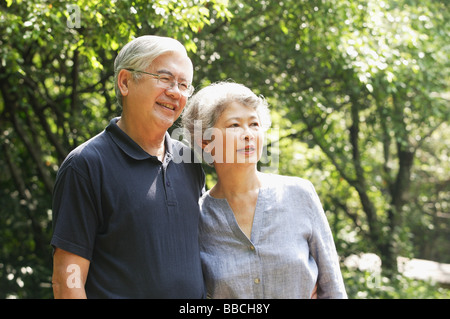Senior couple standing side by side, looking away, smiling Stock Photo
