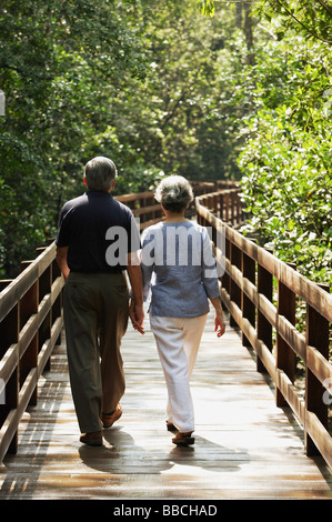 Mature couple walking  on wooden bridge, rear view Stock Photo
