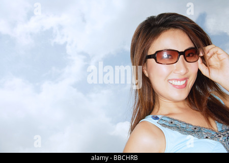 Young woman wearing sunglasses, smiling at camera Stock Photo