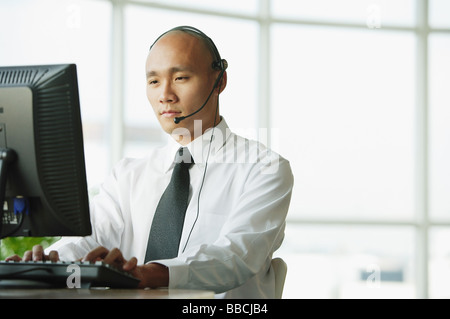 Man with headset, using desktop PC Stock Photo
