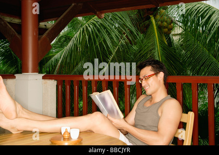Man sitting with feet up on table, reading Stock Photo