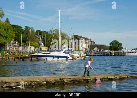 Boy on pier with fishing net, Lake Windermere at Waterhead, Lake District National Park, Cumbria, England UK Stock Photo