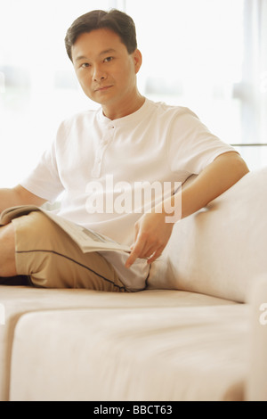 Man sitting on sofa, looking at camera Stock Photo