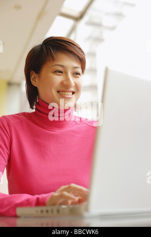 Young smiling black woman using computer and drinking coffee in modern ...