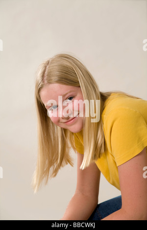 Portrait of 11-12 year old girl caucasian sitting leaning with arms on knees looking camera confident casuals Casually dressed casual clothes USA Stock Photo