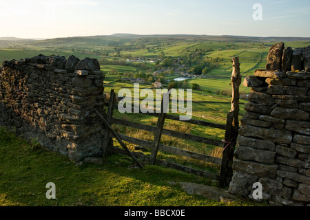 A drystone wall frames the view towards the village of Burnsall, in Wharfedale, Yorkshire Dales, from Burnsall Fell Stock Photo