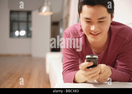 Young man holding mobile phone, text messaging Stock Photo