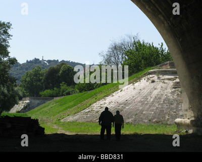 two men walking under bridge in rome italy Stock Photo