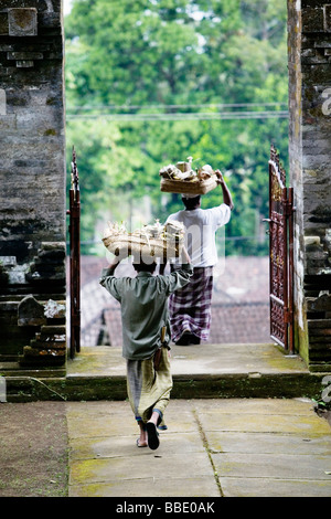 Men carrying food offerings in a Hindu temple in Bali, Indonesia. Stock Photo