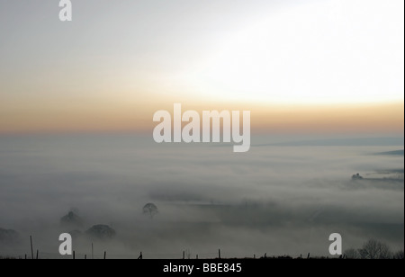 The glow of the setting sun over a sea of mountain mist in the Pennines, west of Halifax, United Kingdom Stock Photo