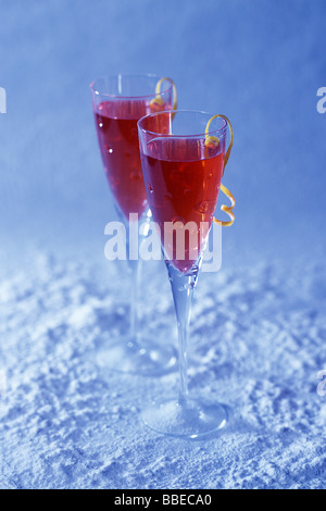 Two Cranberry Champagne Drinks With Lemon Peel Garnish on Snowy Background Stock Photo