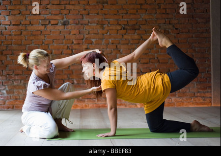 Yoga Teacher With Student, Doing Tiger Pose Stock Photo