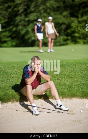 Man Sitting by Sand Trap on Golf Course Stock Photo