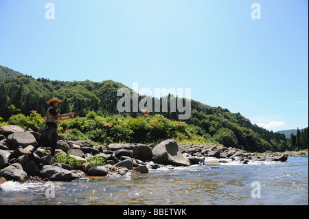 Man with straw hat standing on stone and fishing Stock Photo