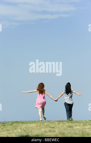 Two young women walking hand in hand outdoors, rear view Stock Photo