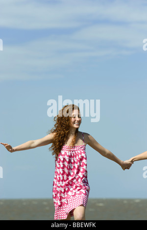 Young woman running with arms out, holding friend's hand, cropped Stock Photo