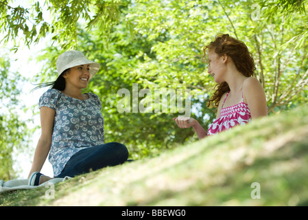 Two young women sitting in park talking, low angle view Stock Photo