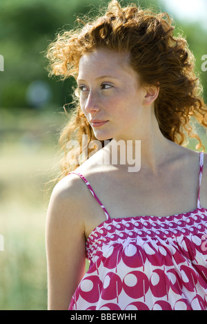 Young red haired woman outdoors, hair blowing in breeze, portrait Stock Photo