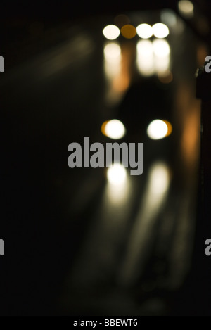 Headlights of traffic speeding along street at night Stock Photo