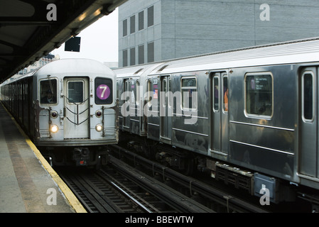 Trains leaving platform of elevated station Stock Photo