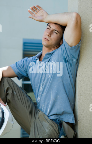 Construction worker holding back of arm to forehead, eyes closed, taking break Stock Photo
