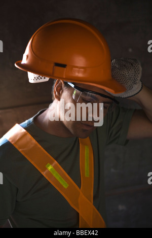 Construction worker taking hard hat off wiping brow with back of hand Stock Photo