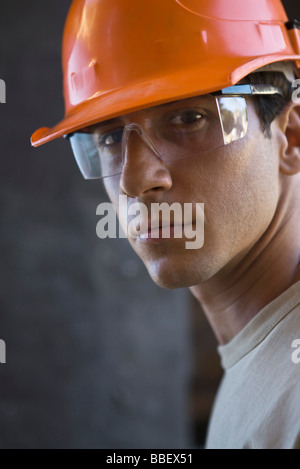 Construction worker wearing hard hat, protective glasses looking at camera Stock Photo