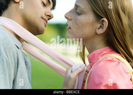 Young couple leaning in to kiss, eyes closed, side view