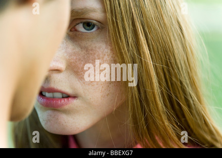 Young woman facing man, staring warily at camera, cropped Stock Photo