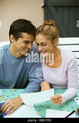 Couple sitting at table, discussing finances, both smiling Stock Photo