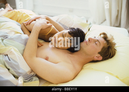 Couple asleep in bed, woman's head resting on man's chest Stock Photo