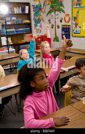 inter racial diversity racially diverse multicultural multi cultural interracial 3rd grade student 8-10 year old enthusiastically raise hands class Stock Photo