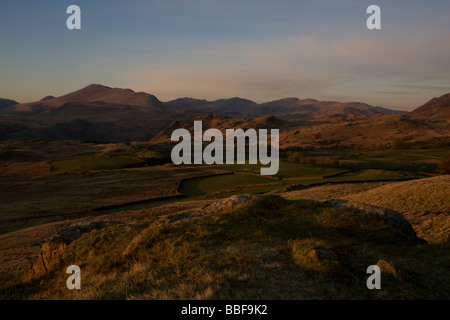 Soft sun shines on the farmland around the Old Man of Coniston in the Lake District. Stock Photo