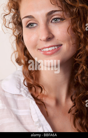 Close up of face of an attractive young women with curly brown hair smiling Stock Photo