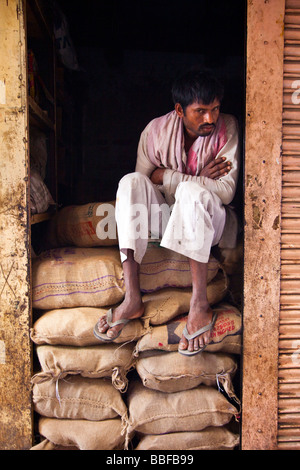 Indian Porter Resting on Burlap Sacks in Old Delhi India Stock Photo