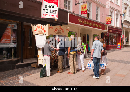 Customers queing up outdoors in the street to buy fresh ice cream from a stall in Norwich Norfolk Uk from Ronaldo Stock Photo