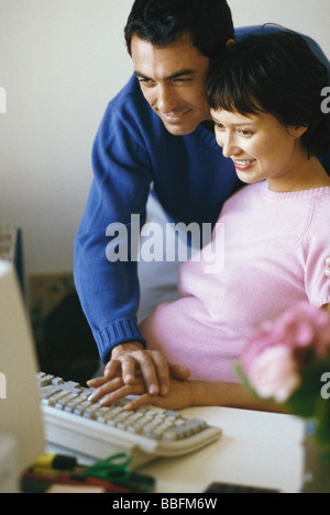 Couple using desktop computer together, man's hand resting on woman's hand Stock Photo