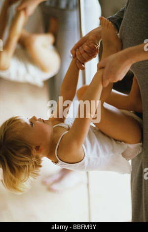 Little girl holding mother's hands, turning flip against her stomach Stock Photo