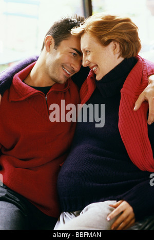 Expecting couple embracing, smiling Stock Photo