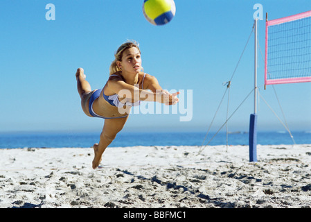 Female playing beach volleyball, diving to catch ball Stock Photo