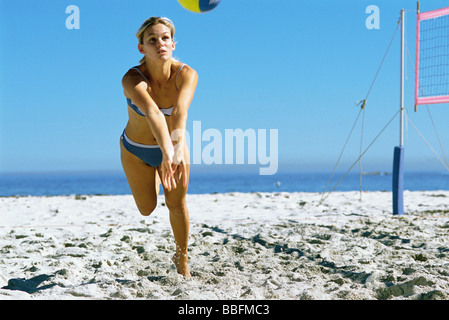 Female playing beach volleyball running to catch ball Stock Photo