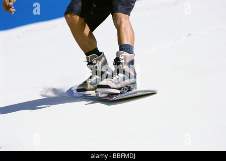 Sandboarder sliding down dune, close-up of feet on board Stock Photo