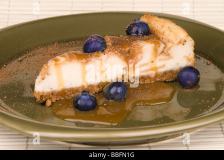 A slice of caramel coated cheesecake with blurberries and nutmeg sprinkles Stock Photo