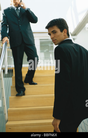 Businessman going up steps, looking over shoulder at camera Stock Photo
