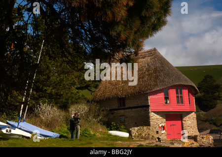 Birdwatchers on the South Devon coast beside the traditional thatched boasthouse at Bantham in Jennys Cove UK Stock Photo