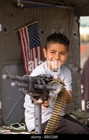 A young boy plays with a machine gun in the back of a Huey Helicopterat the Hemet Ryan Air Show Stock Photo